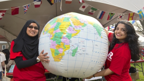 Two students holding up an inflatable globe