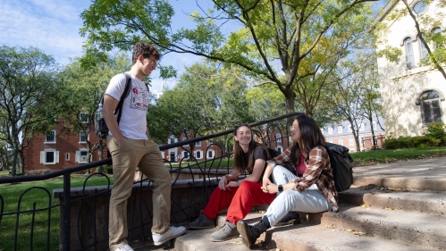 Students stop and talk on a stairway on College Ave Campus