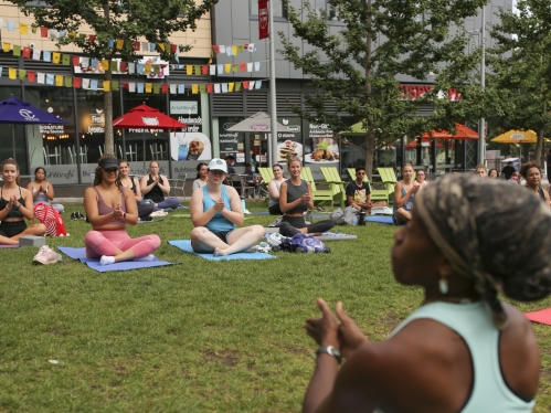 Students and an instructor sit cross-legged in the grass at the end of an outdoor yoga session at Rutgers