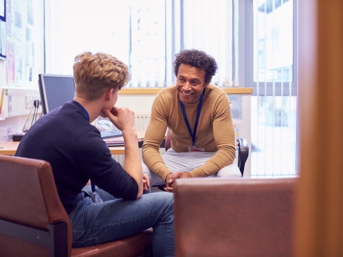 Male College Student Meeting With Campus Counselor Discussing Mental Health Issues