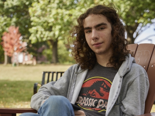 A student sits in an adirondak chair outside on campus