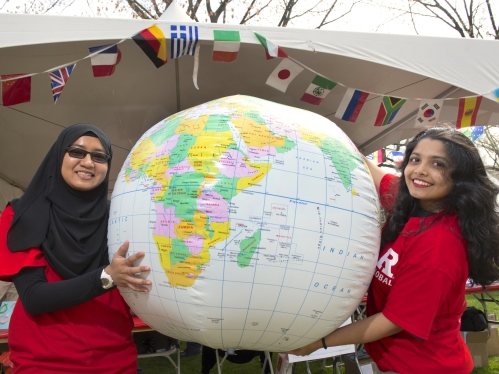 Two students holding up an inflatable globe