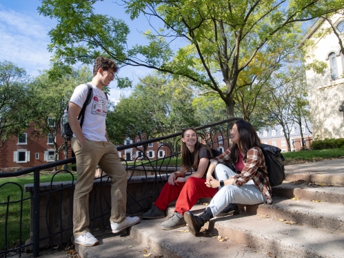 Students stop and talk on a stairway on College Ave Campus