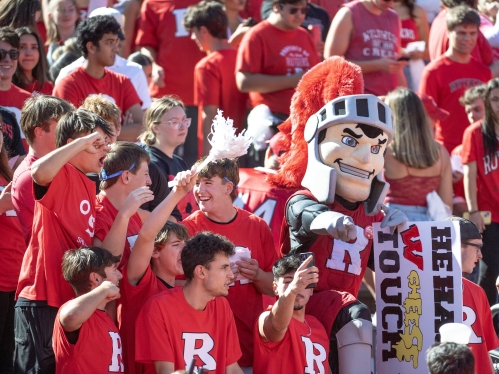 Students in the stands with the Scarlet Knight at a football game
