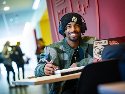 Student sitting at a table with a notebook and laptop